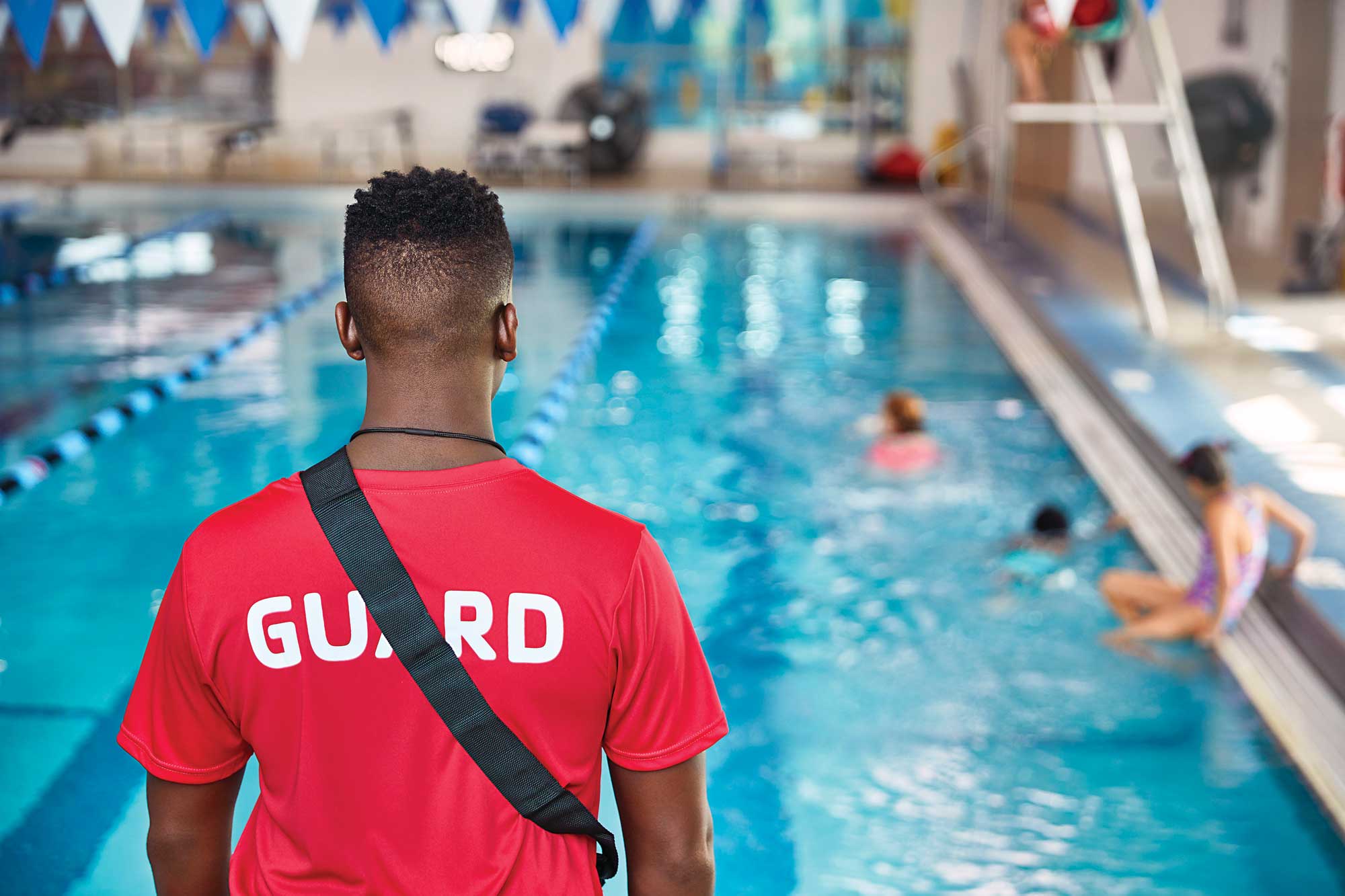 Lifeguard, standing facing pool
